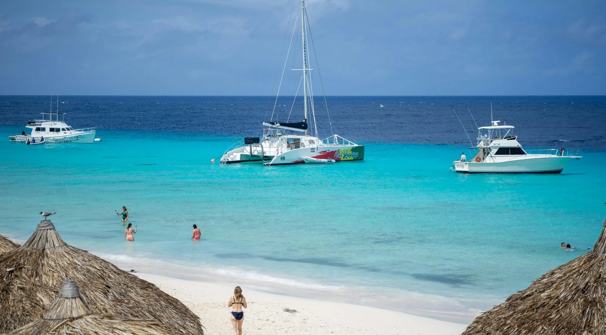 Catamarans and motor yachts anchored off Klein Curaçao beside the beach palapas