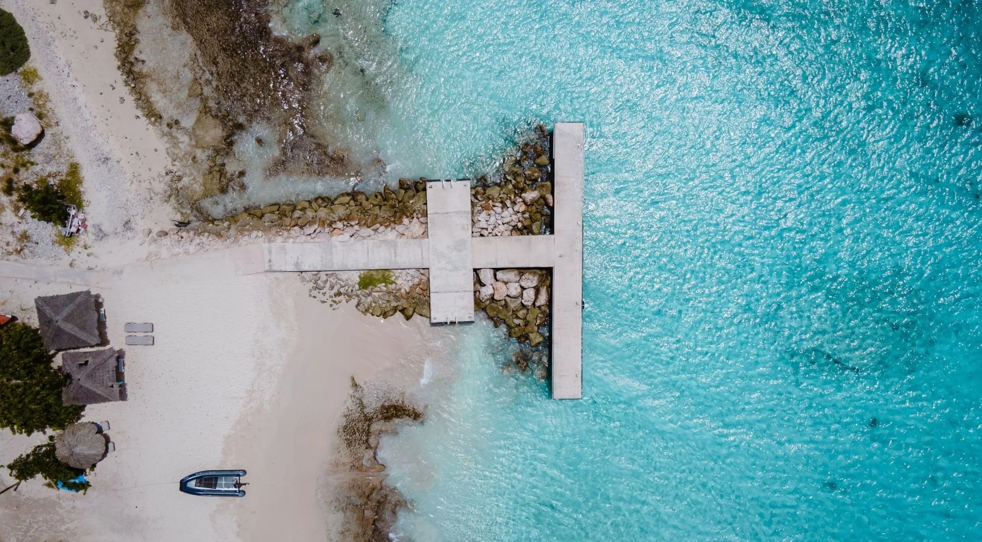 Top-down aerial of Klein Curaçao's concrete landing pier running out over clear turquoise water