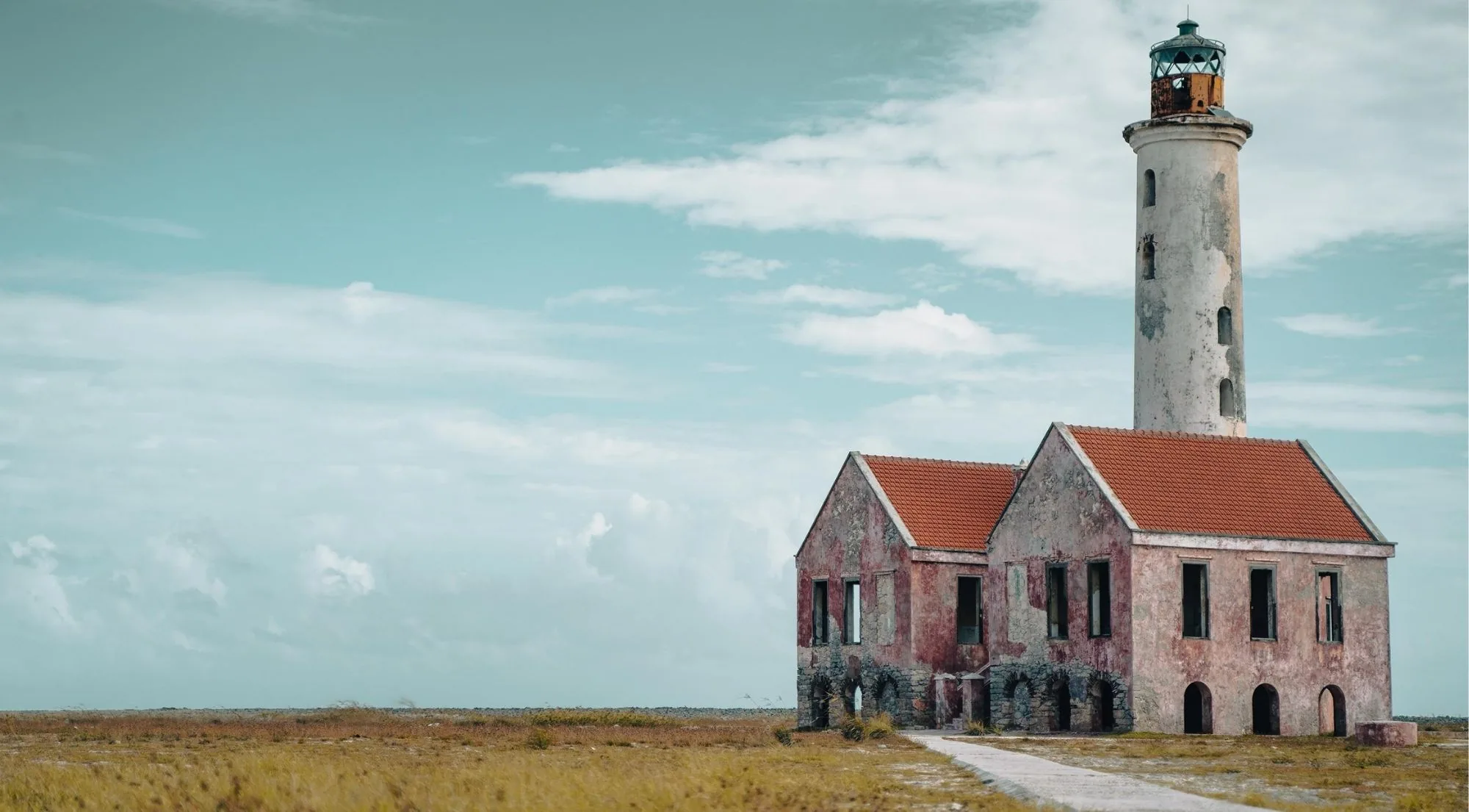 The pink lighthouse and abandoned keeper's house standing on Klein Curaçao's open scrubland