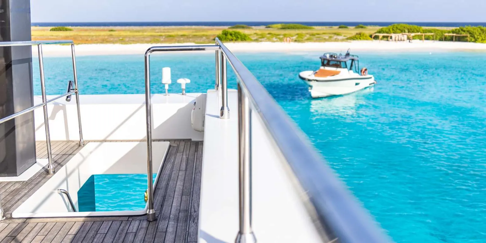 The catamaran yacht's side deck and boarding gate above clear turquoise water