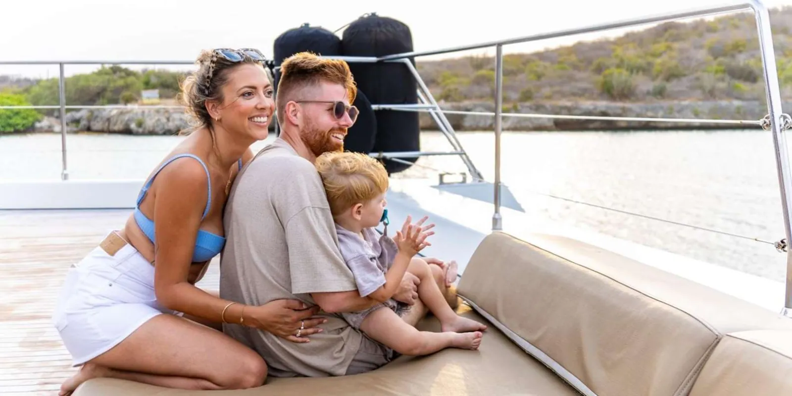 A family with a toddler seated on the catamaran's shaded aft deck