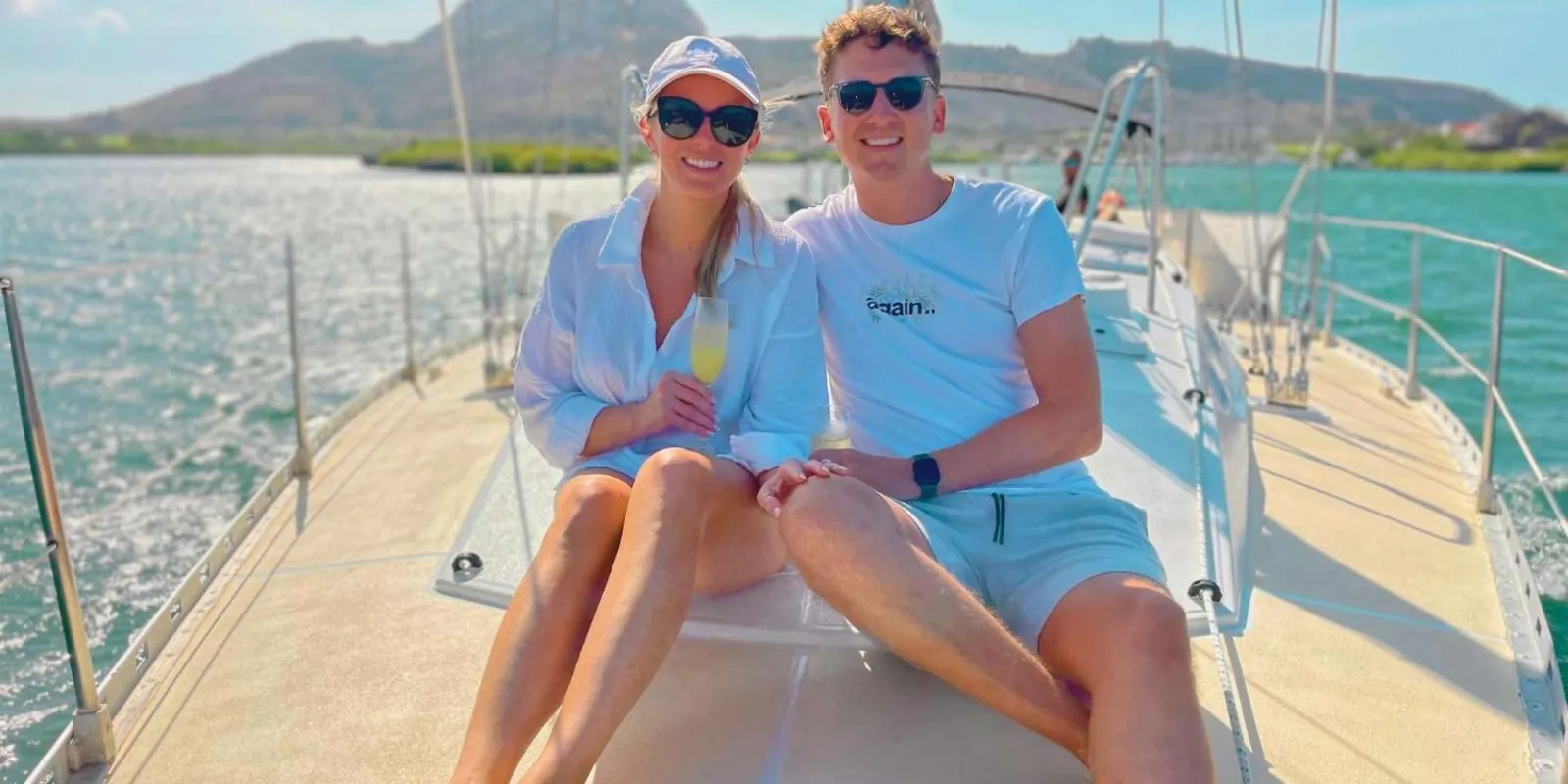 A couple with drinks on the Gold Seahorse's foredeck as it leaves the marina