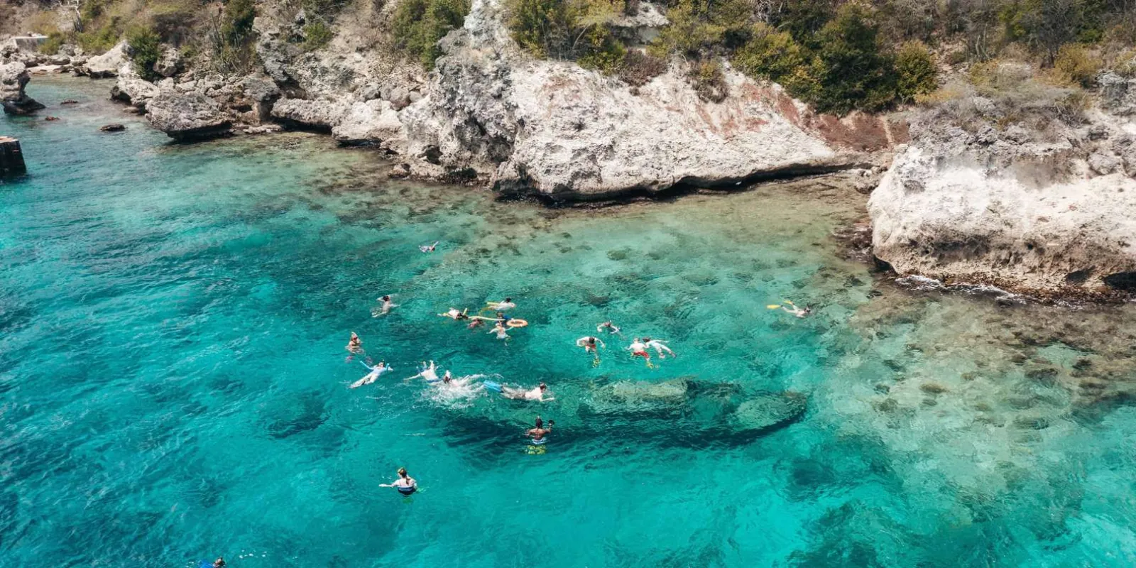 Snorkelers in the clear shallows directly above the sunken tugboat